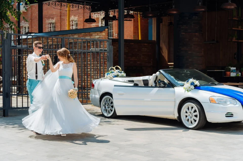 beautiful-bride-and-groom-pose-beside-their-luxury-car-hire-for-the-wedding